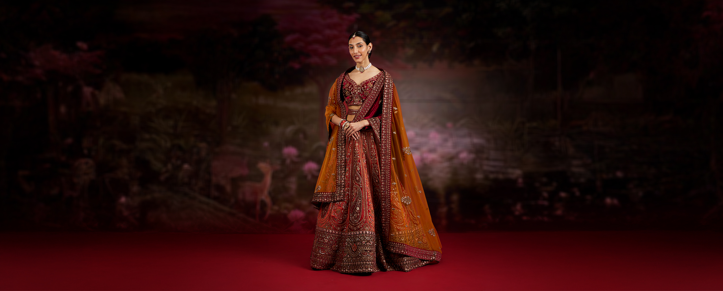 Woman elegantly dressed in a stunning red lehenga, perfect for a winter wedding look.
